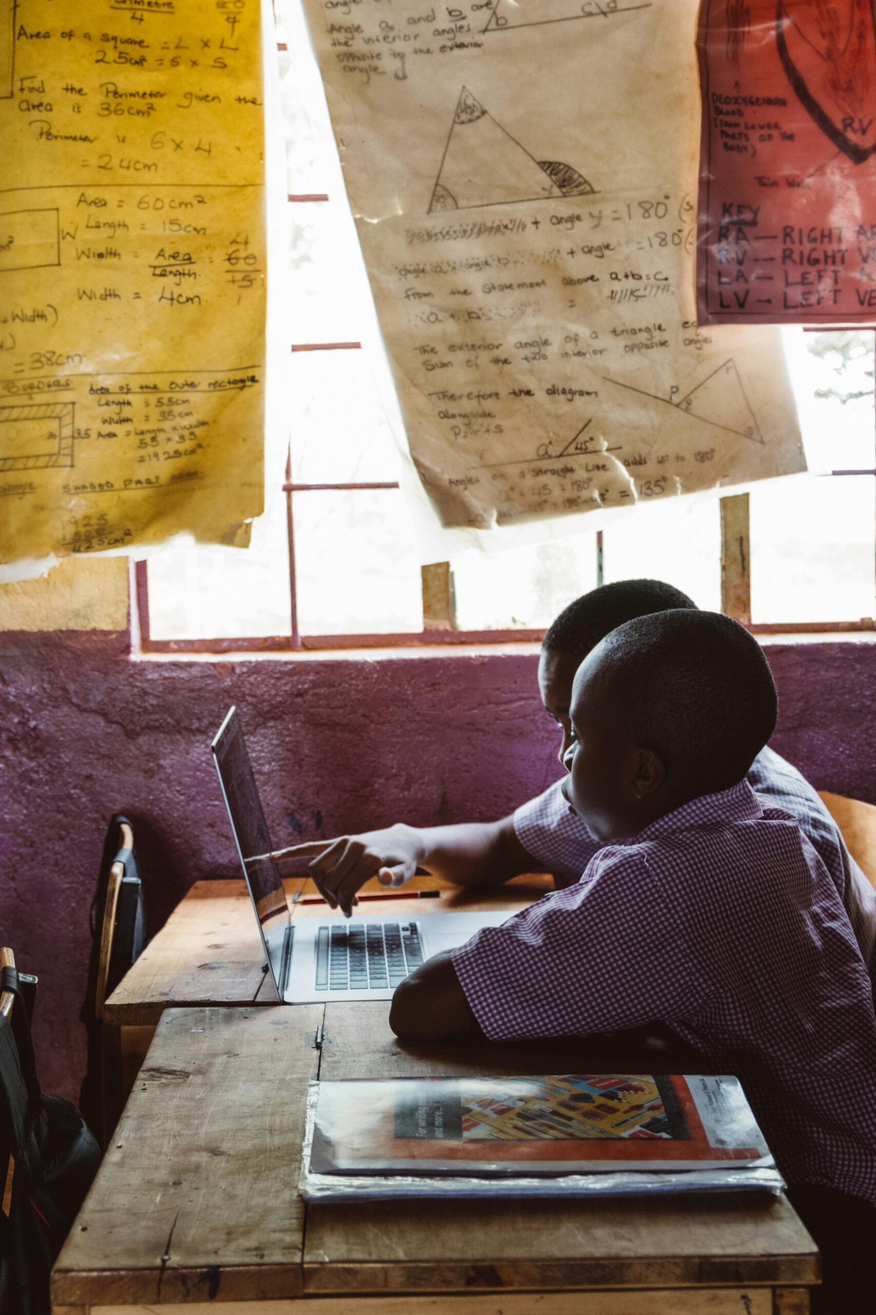 AMIDERA Two boys collaborate on a laptop together in a classroom setting under natural light.